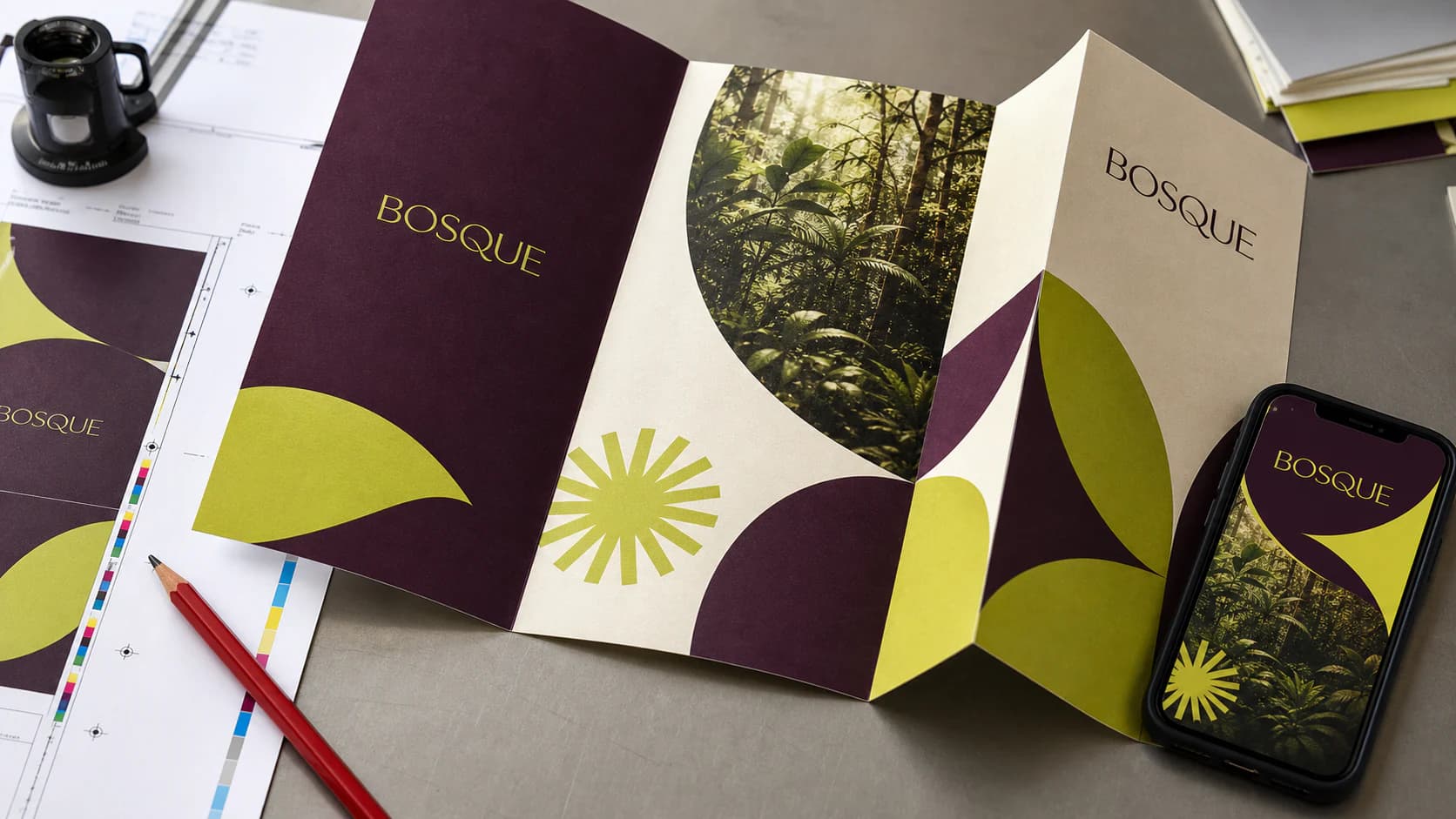Folder impresso da marca fictícia Bosque em tamanho real ao lado do celular usado para aprovar a arte